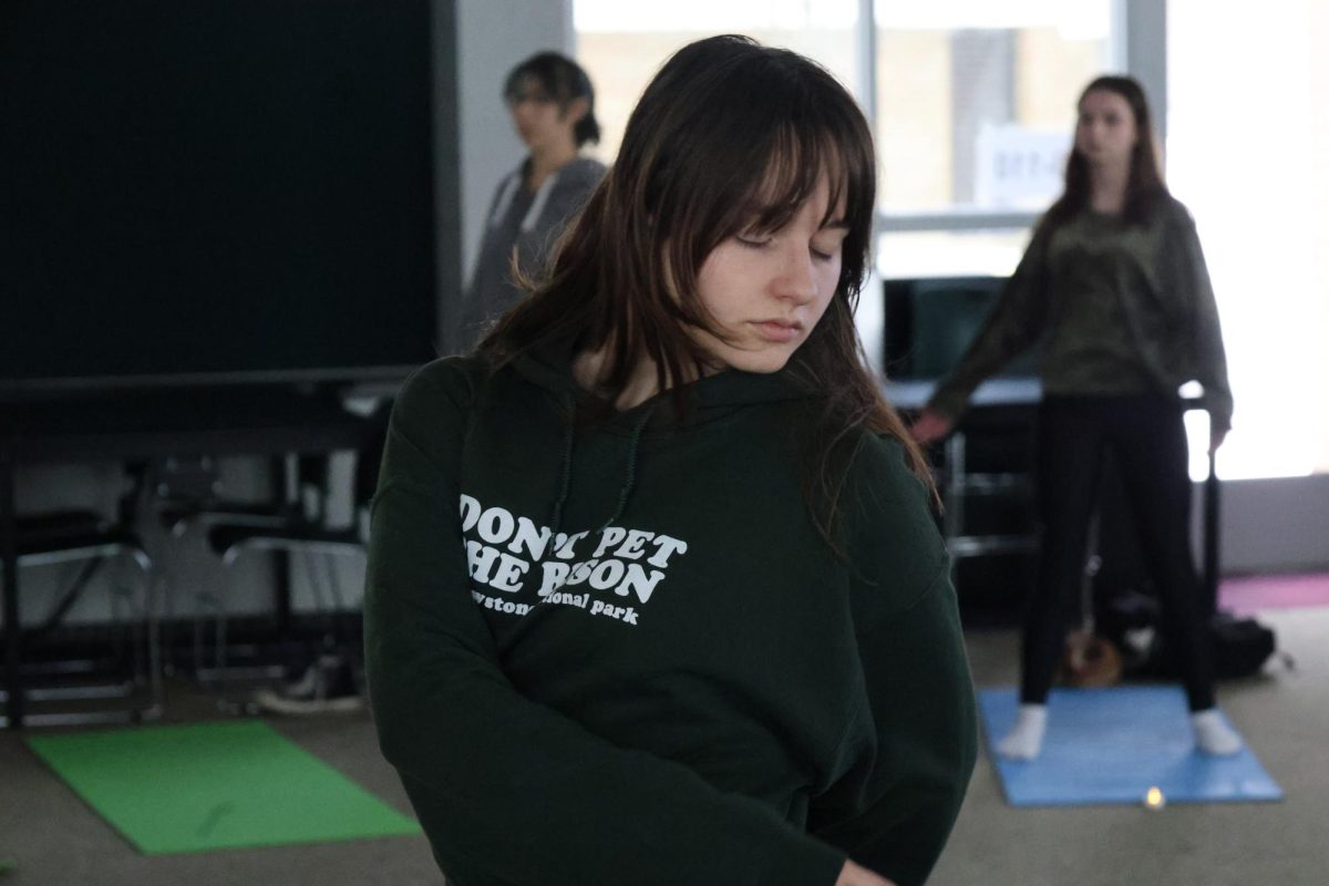 Looking over her shoulder, senior Julia Martin is stretching. On Dec. 9, yoga with Sunny took place during SRT. 
