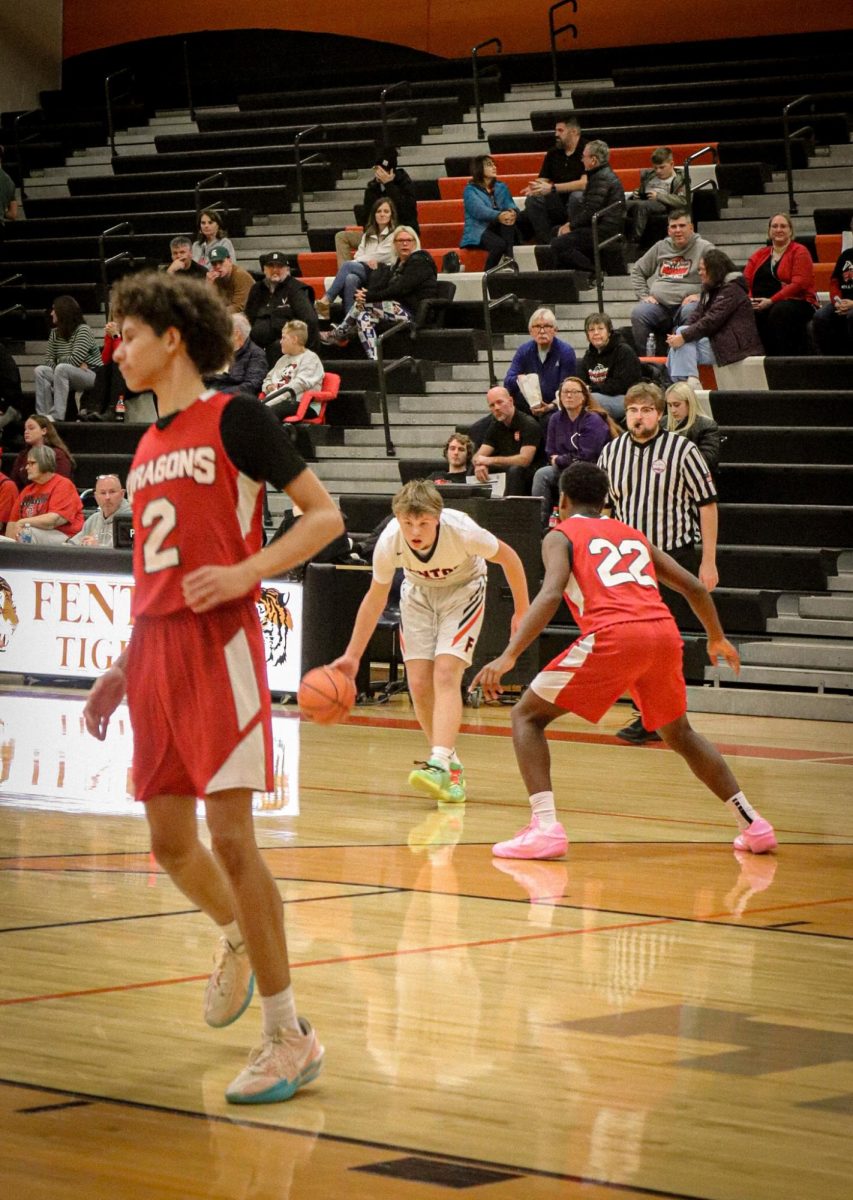 Getting ready to pass the ball, freshman Leo McCaughan and his team play against a competitive opponent. On Dec. 11, the Fenton Tigers' freshman team plays against Wartburg and loses 57-33. 