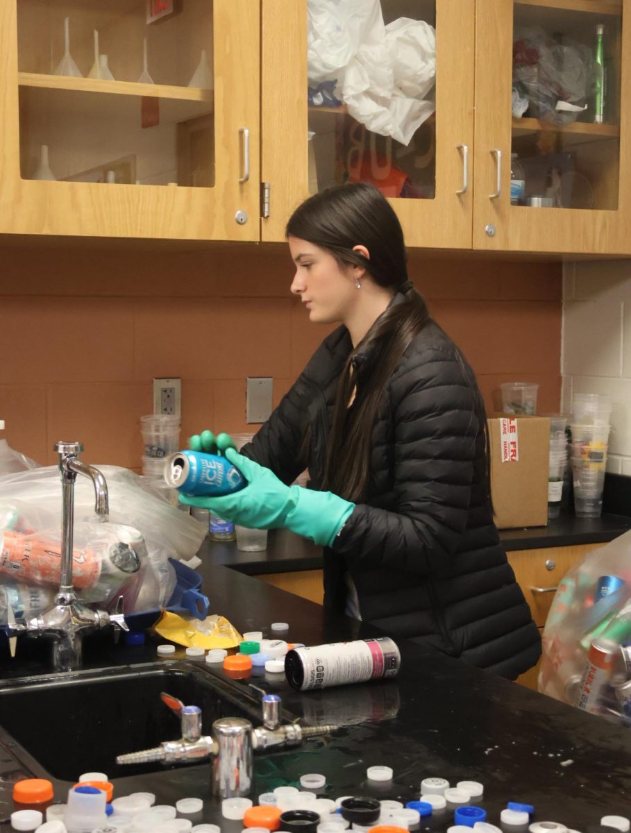 Going through the garbage bag, sophomore Gia Hessling is recycling cans. On Dec. 9, ECO club collected the recycling bins around the school to help raise money. 