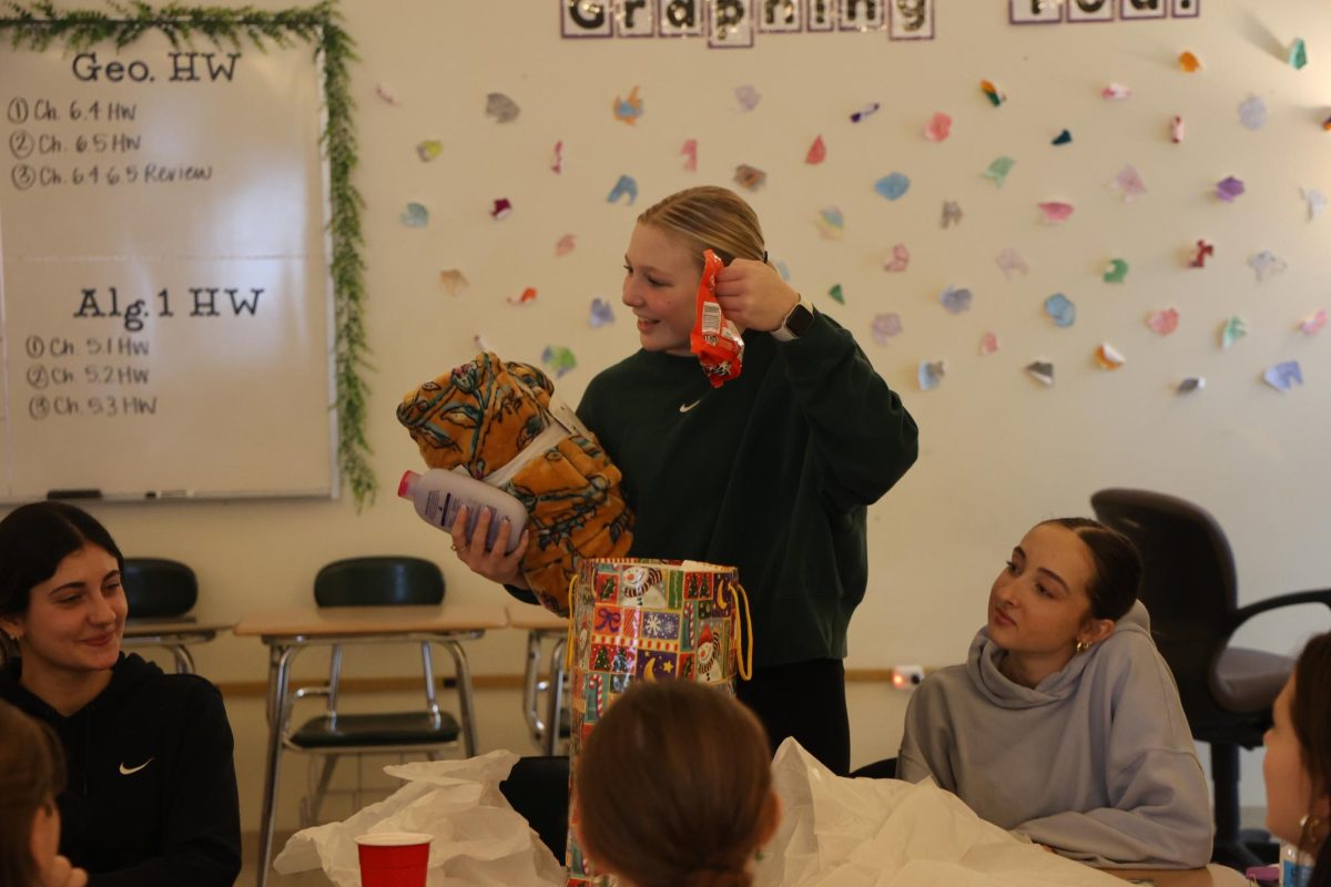 Showing off her gift, junior Kyla Moore participates in a Secret Santa exchange with her teammates. On Dec. 19, the Fenton dance team held a party inside Mrs. Jeffreys' room.