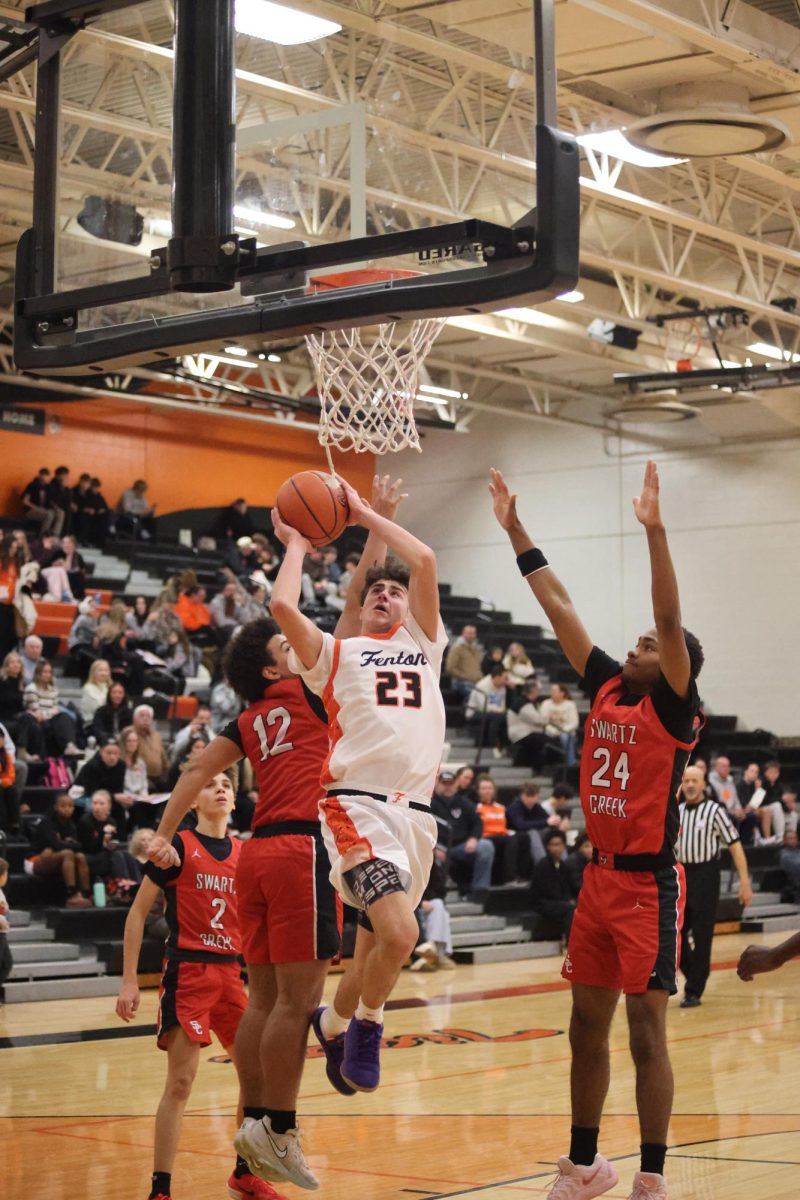 Going for a layup, junior Zack Pearson is contested at the rim. On Jan. 23, the Fenton varsity basketball team played Swartz Creek and won 56-50.

