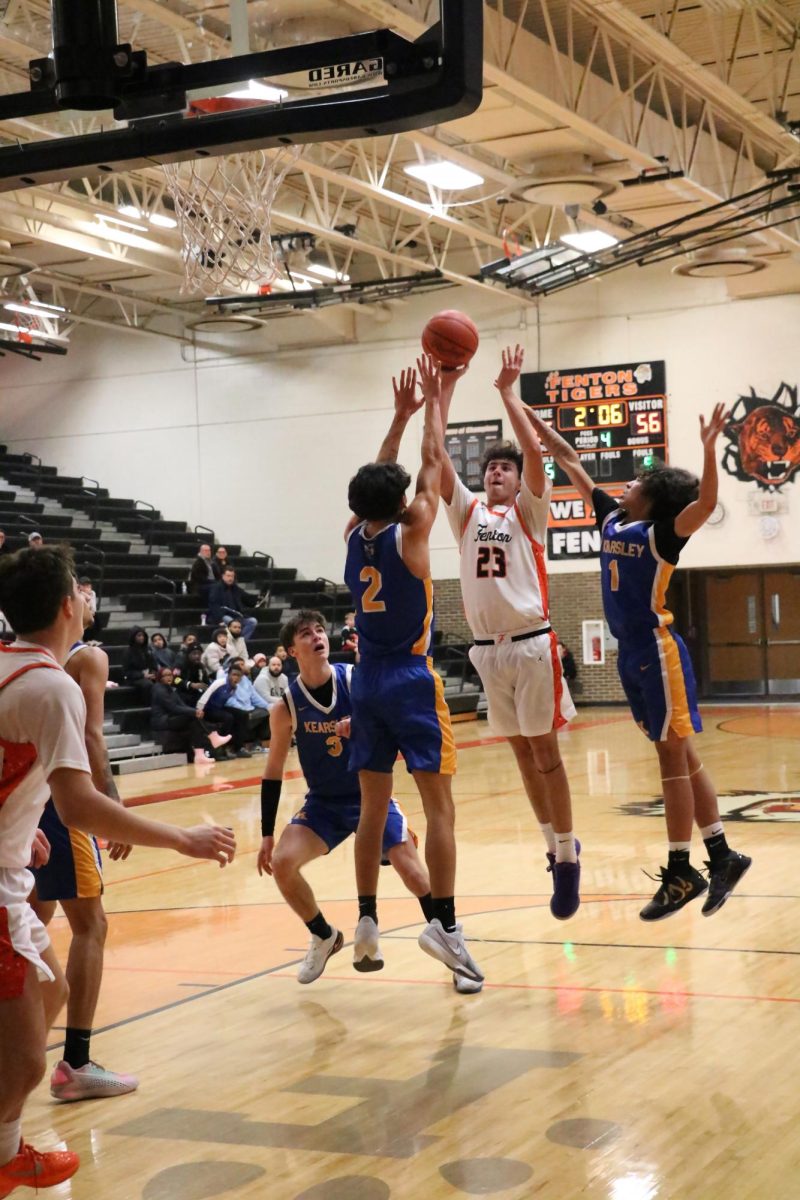 Shooting the ball, junior Zack Pearson moves past the defenders. On Jan. 7, the Fenton varsity basketball team went up against Kearsley, losing 56-59.