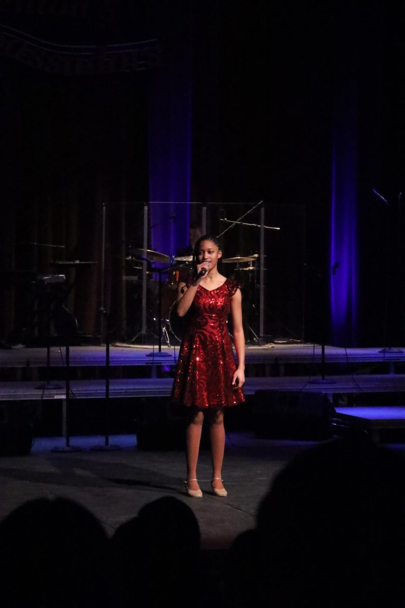 Looking out to the crowd, Senior Kierstyn Rutley sings her solo in the Abassorsder concert. On Feb. 21, Fenton Ambassadors hold a Back by Popular Demand concert.