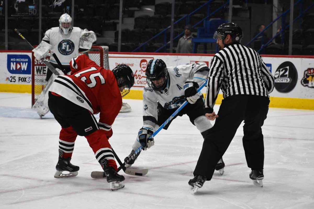 Competing in a face-off, junior Trenton Rockman keeps his eyes on the puck. On Jan. 31, the Griffins went up against Freeland.