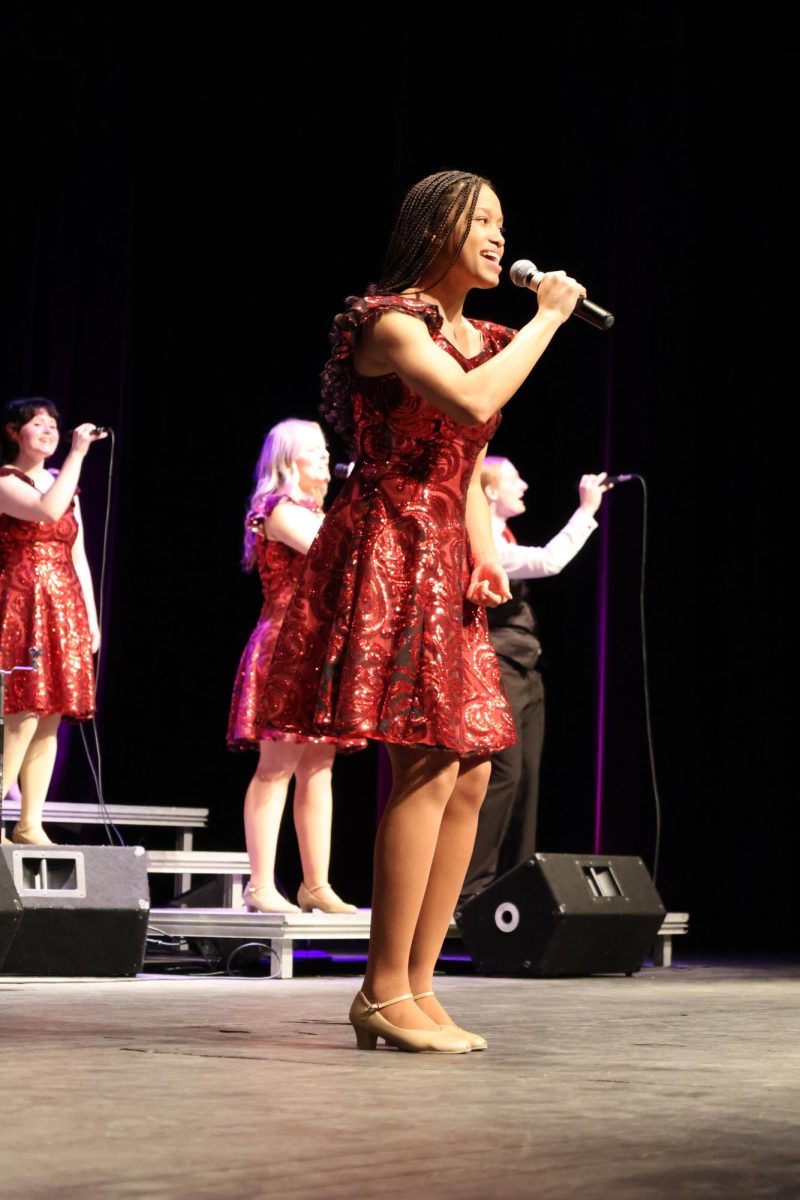 Holding the microphone, Senior Kierstyn Rutley sings her solo in the Abassorsder concert. On Feb. 20, Fenton Abbasenders hold a Back by Popular Demand concert.