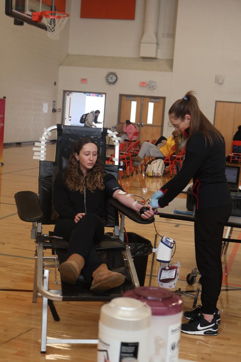 Looking down at her arm, senior Reese Russo draws her blood. On Feb. 20, Versiti blood center holds a blood drive for Fenton High School.