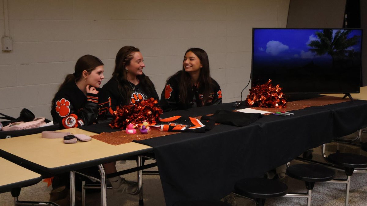 Supporting the cheer team, Junior Kenna Bigger, Marissa Miller, and Lilly Brawner are talking about their cheer team. On Feb. 2, they convince the 8th graders to join Fenton cheer.
