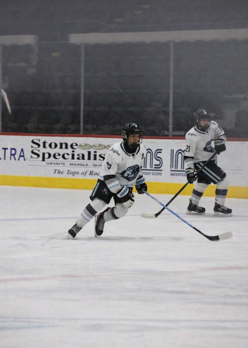 Skating on the ice, junior Trenton Rockmen moves toward the puck. On Jan. 31, the Griffins hockey team faced Freeland High School and lost 5-1.