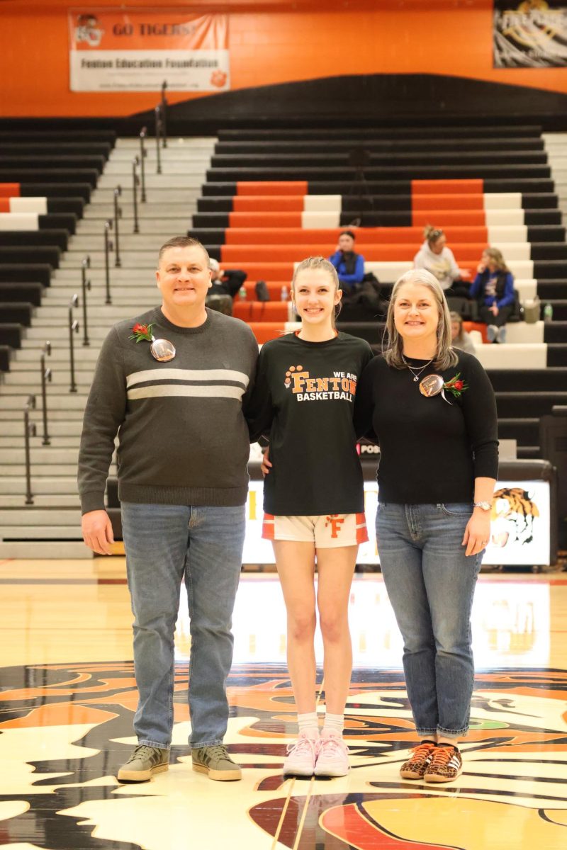 Standing with her parents, senior chole Ketcum smiles for a photo with her parents. On feb 3 fenton girls basketball had their senior night. 

