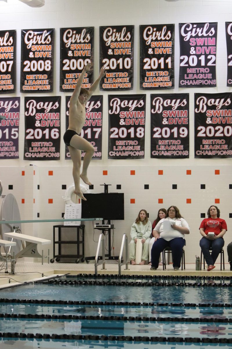 Getting ready to dive, senior Keegan Myers begins to jump in the pool. On Feb. 12, the Fenton Varsity Boys Swim and Dive team had a meet home against Holly.