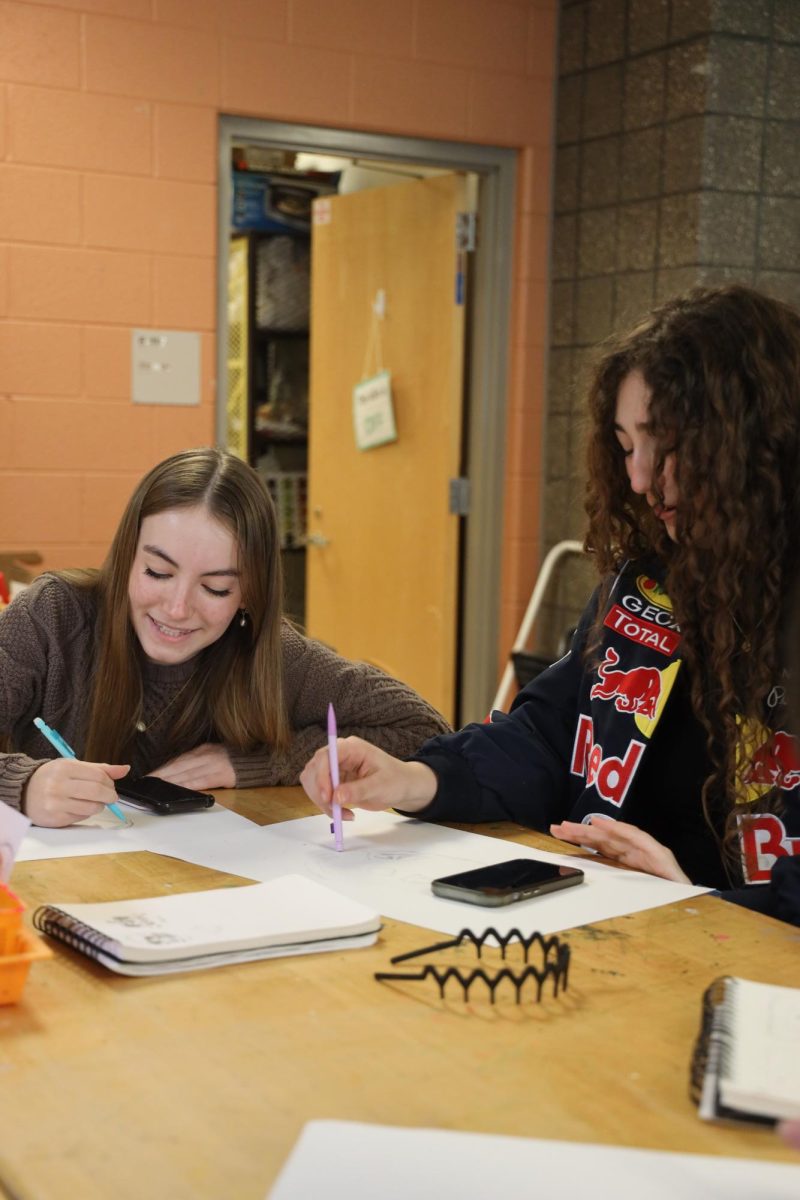 Drawing together, sophomores avita wallace and penny lennox work on finishing their drawings for art class. On Mar 19, the art class turned in their projects. 