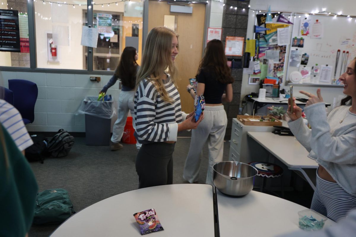 Pouring candy into the bowl, sophomore Ava Roberts participates in doing a class candy salad. On March 20, the advanced publications class had a family friday.