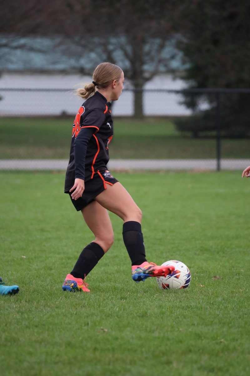 Caption prepping to kick the ball, freshman Alissa York takes the ball upfield. On April 10, the varsity girls' soccer team played Powers and won 