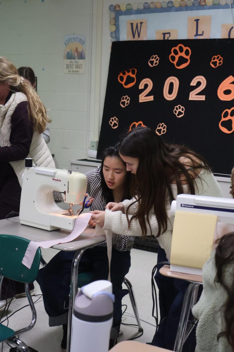 Cutting the fabric, Senior Isabel Bhagat and Alicia Verscheure learn how to sew a scrunchie. On April 9, Renae Muzer hosts a "how-to-sew" class during SRT.
