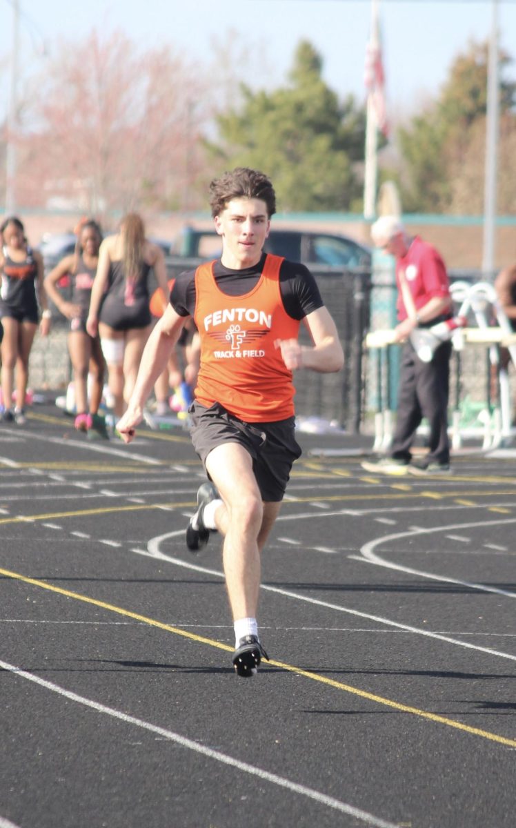 Running around the track, freshman Caleb Miller races in the 100-meter dash. On April 14, Fenton competed against Holly and Flushing and placed 2nd. 