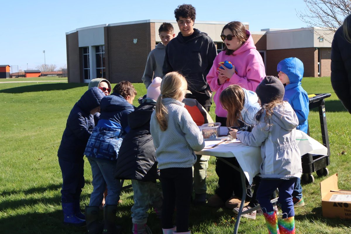 Handing out the card, Sophomore Jabin Abujaish and Isabella Murto help with activities for the kids. On April 20, Eco club students help out with pond day.