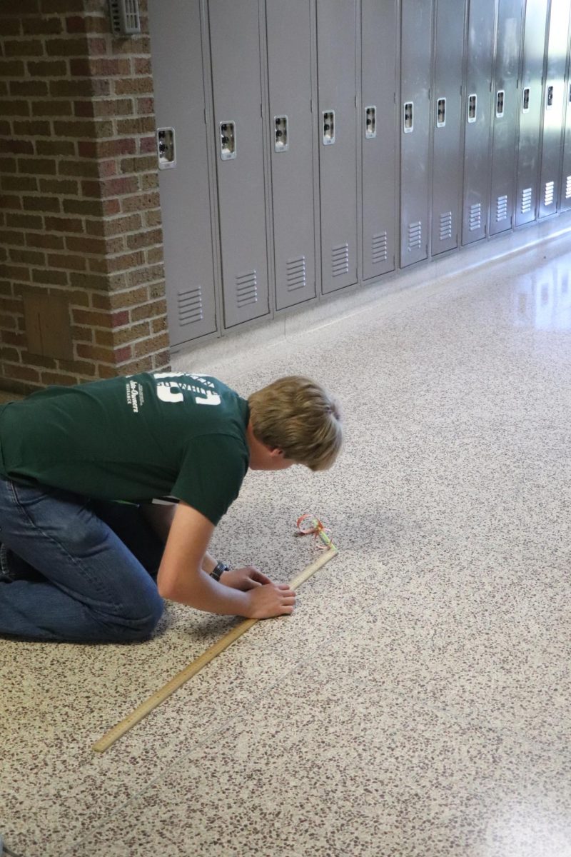 Measuring the drop, freshman Anderson Frieden measures how far his bird lab went. On April 20, the biology classes did a bird lab.